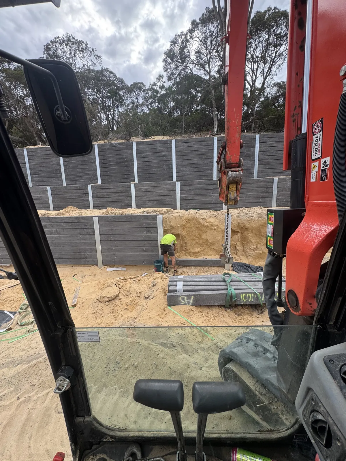 View from the excavator cab as a tiered charcoal sleeper wall goes in